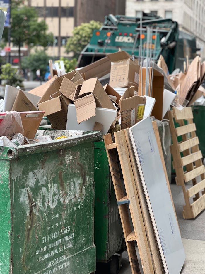 services-02 Piled cardboard boxes and waste in a city dumpster highlight urban recycling.